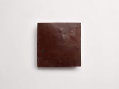 a square piece of chocolate sitting on top of a white table next to a wall