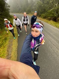 a group of people running down a road in the rain with one person taking a selfie