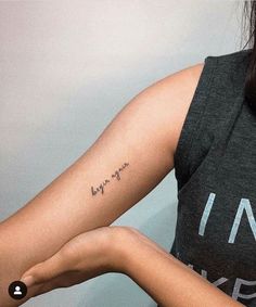 a woman with a small tattoo on her arm and the word love is written in cursive writing