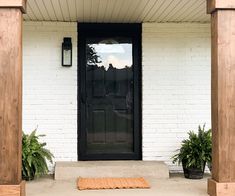 a black front door on a white brick house with potted plants in the foreground