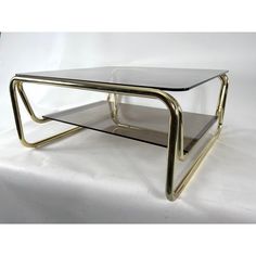 a glass and brass coffee table with two shelves on each side, in the shape of a rectangle