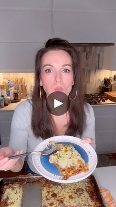 a woman holding a plate with food on it in front of her face and looking at the camera