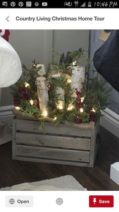 a christmas tree in a wooden crate with candles on it and lights around the branches