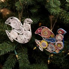 two ornaments hanging from a christmas tree decorated with rolled up origami bird shapes