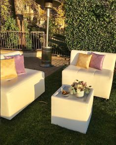 two white couches sitting on top of a lush green field