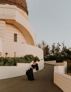 a man and woman kissing in front of a building with palm trees on the side