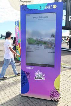 a man walking past a purple and blue kiosk