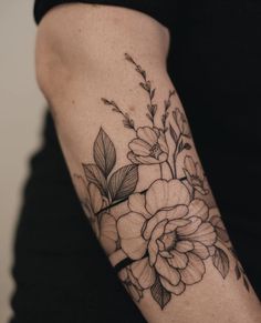 a woman's arm with flowers and leaves on it