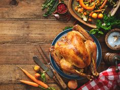 a roasted turkey on a blue plate surrounded by fresh vegetables and other thanksgiving food items