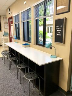 an empty waiting area with stools and tables in front of the window that reads, this is where we are able to sit