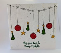 a christmas card with ornaments hanging from strings and stars on the string that says, merry & bright