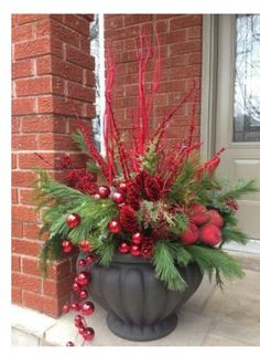 a potted plant with red berries and greenery on the outside of a house