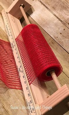 a red piece of cloth on top of a wooden ruler with a measuring tape next to it