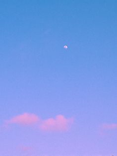 the moon is in the blue sky above some trees