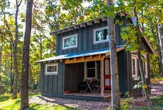 a small cabin in the woods with trees surrounding it