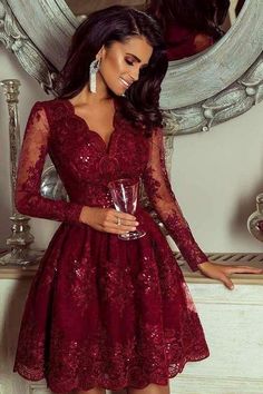 a woman standing in front of a mirror wearing a red dress and holding a wine glass