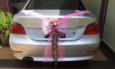 a white car with pink ribbon and flowers on it