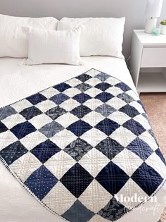 a blue and white quilt on top of a bed in a room with two nightstands