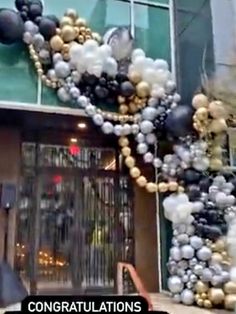 an entrance to a building decorated with black, white and gold balloons