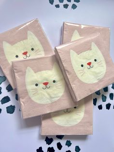 three pink napkins with white cats on them