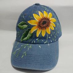 a blue hat with a sunflower painted on it's front and back side