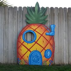 a painted pineapple on the side of a fence