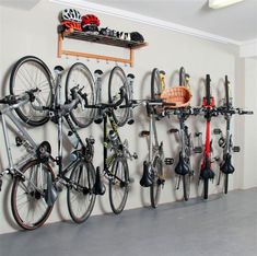 there is a bike rack with many bikes on it in the room, and several bicycles are hanging up against the wall