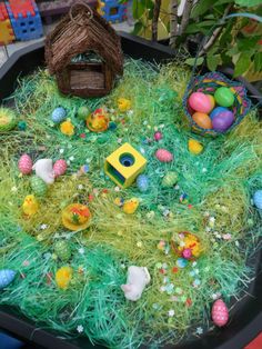 a tray filled with fake grass covered in easter eggs and other decorations on top of it