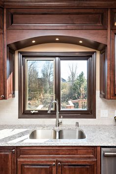 a kitchen with wooden cabinets and a double pane window above the sink in front of it