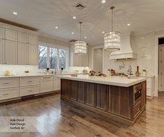 a large kitchen with an island in the middle and two chandeliers hanging from the ceiling