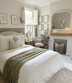 a bedroom with white bedding and pictures on the wall above it, along with a fireplace