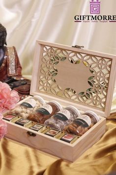 a wooden box filled with assorted items on top of a gold cloth covered table