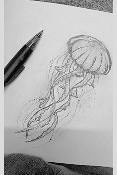 a drawing of a jellyfish on paper next to a pen and ink dot pens