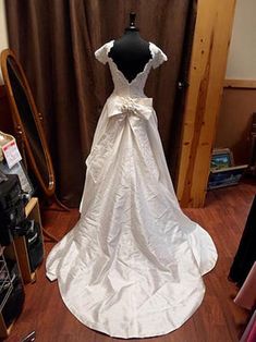 a white wedding dress on display in front of a mirror with other items around it