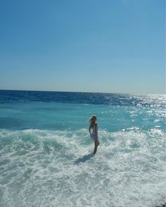 a woman standing in the ocean with her back to the camera