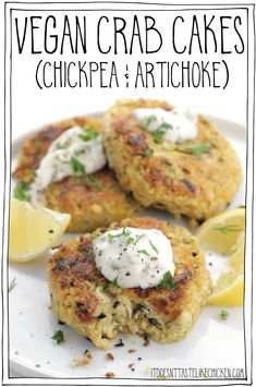 two crab cakes on a white plate with lemon wedges and sour cream drizzled on top