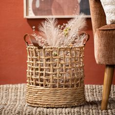 a wicker basket with feathers in it sitting on a rug next to a chair