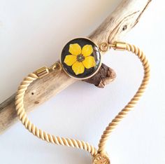 a yellow flower is attached to a rope bracelet