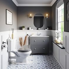 a white toilet sitting in a bathroom next to a sink under a mirror and a window