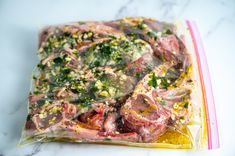 a piece of meat sitting on top of a plastic bag filled with vegetables and seasoning