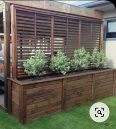 a wooden planter box with plants growing out of it on top of green grass