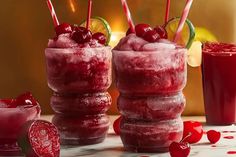 three glasses filled with red liquid and topped with cherries