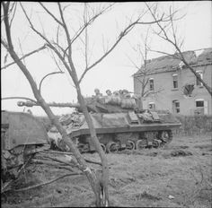 an old black and white photo of tanks in front of a house with no trees