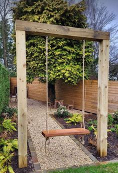 a wooden swing in the middle of a garden