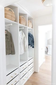 an organized closet with white drawers and baskets