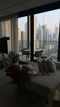 a living room filled with furniture and a large window overlooking the cityscape in the distance