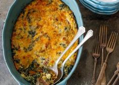 a casserole with cheese and spinach in a blue dish next to silverware