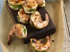 grilled shrimp on a wooden cutting board with garnishes and seasonings