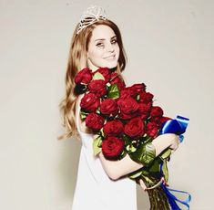 a beautiful young woman holding a bouquet of red roses