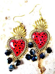 Beautiful and unique earrings made and hand-painted with a polka style brush in red and black, adorned with black glass beads, protected with several layers of high quality jewelry varnish, protecting the paint and making them look even more beautiful. These sacred heart earrings are inspired by Frida Khalo and hand painted Talavera style, part of our Mexican culture, they are the ideal complement for any occasion that will surely enhance your beauty since they are unique pieces, the ideal gift for Mother's Day and holidays. Features/ Product info: -Large: 2 in  (Please see the photos, this design comes in two sizes.) The Main Material: Zinc Alloy (Silver) Color: Black and Red - Earrings: 3 in (H) 1.75 (W) -Earrings weight: 7 grams (each) -The hooks are hypoallergenic Jewelry Love: Your Es Hand-painted Red Jewelry For Valentine's Day, Hand Painted Red Jewelry For Valentine's Day, Red Heart-shaped Hand Painted Jewelry, Whimsical Red Hand Painted Jewelry, Artistic Heart Earrings As Gift, Artistic Heart-shaped Earrings For Gift, Nickel-free Jewelry For Valentine's Day Festival, Valentine's Day Enamel Dangle Earrings, Handmade Adjustable Earrings For Valentine's Day